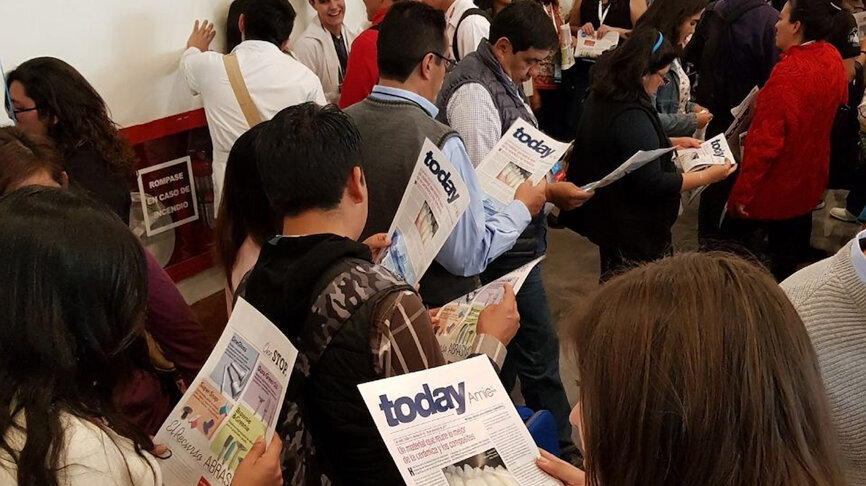 Un grupo de odontólogos lee AMIC Today, el periódico de ferias de Dental Tribune.