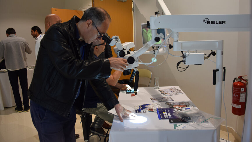 ROOTS SUMMIT attendee trying out a dental surgical microscope from Seiler. 