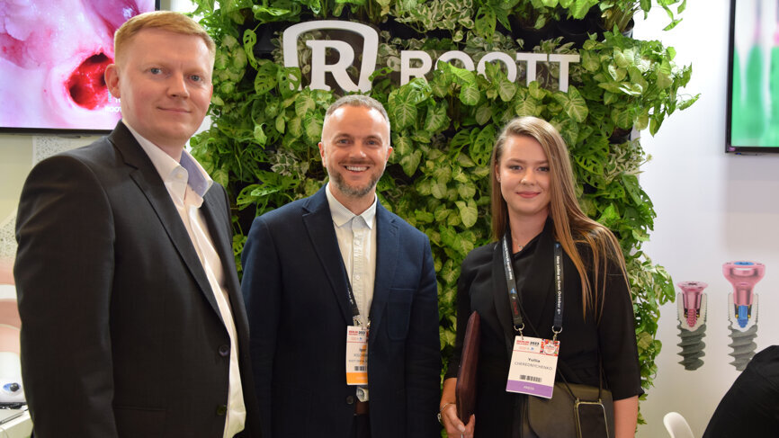Two representatives from ROOTT DENTAL IMPLANTS (left) socialising with a representative of Dental Tribune International.