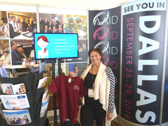 AAID Membership Manager Nicole Basso displays an item from the AAID-branded scrubs collection that’s for sale in the AAID booth. 