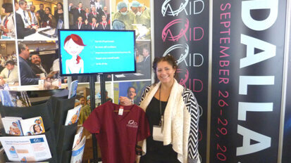 AAID Membership Manager Nicole Basso displays an item from the AAID-branded scrubs collection that’s for sale in the AAID booth.