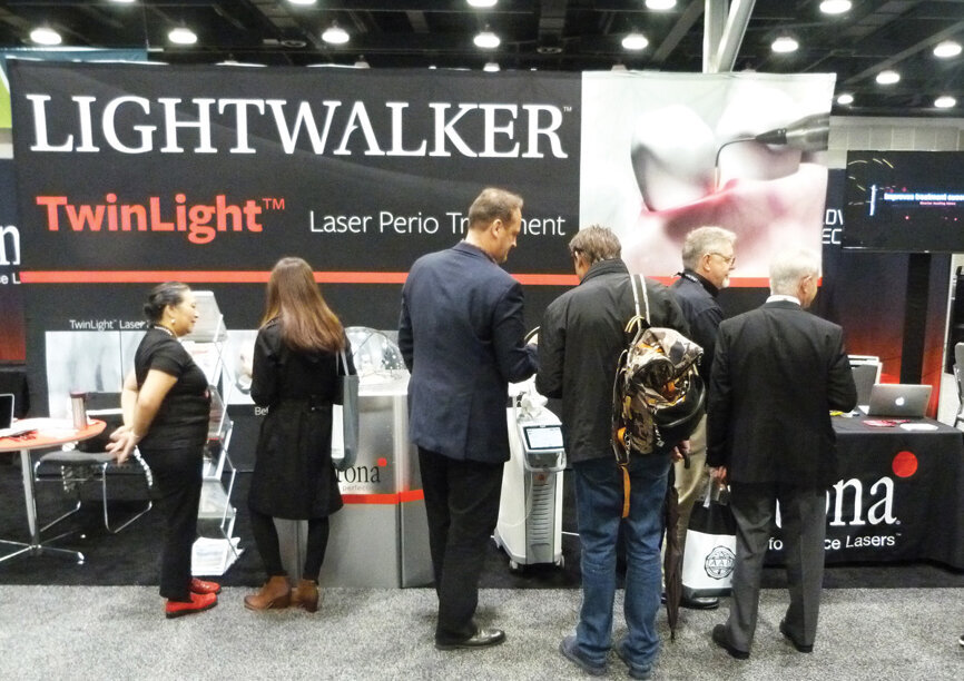 Attendees visit the Fotona booth, where Tess Mandapat, Tom Newman and David Williams offer hands-on demonstrations of the Lightwalker laser. (Photo: Sierra Rendon/DTA)