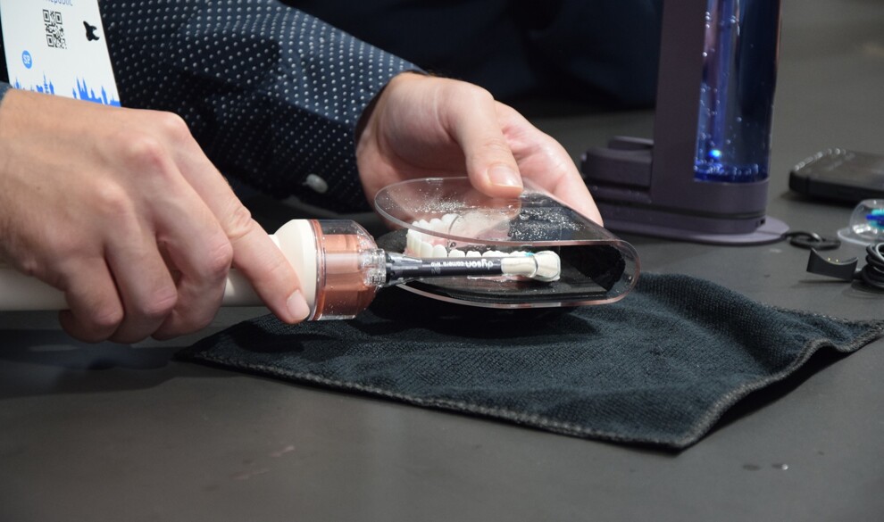 The CameraJet was demonstrated on a dental model during the presentation. Its camera-based targeting system identifies interdental spaces and activates a targeted jet of mouthrinse during brushing.