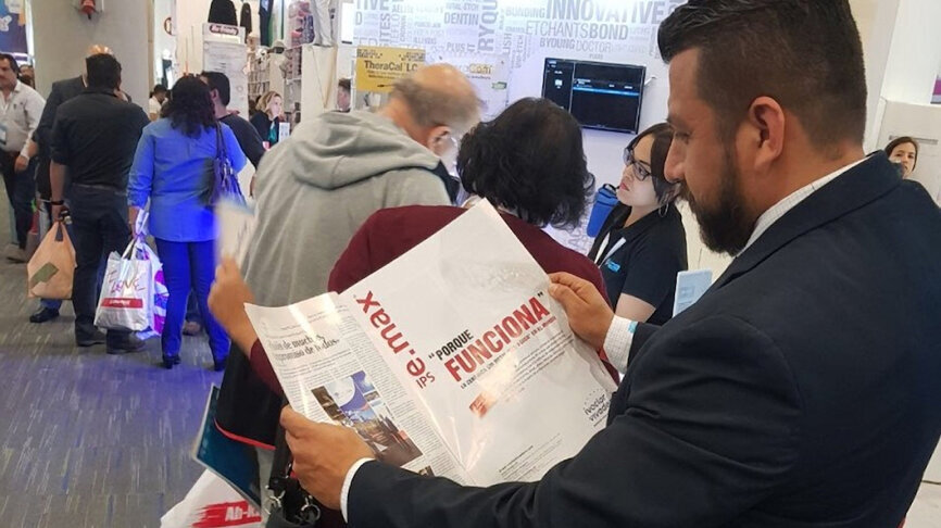 Un dentista mira el anuncio de Ivoclar en Dental Tribune.