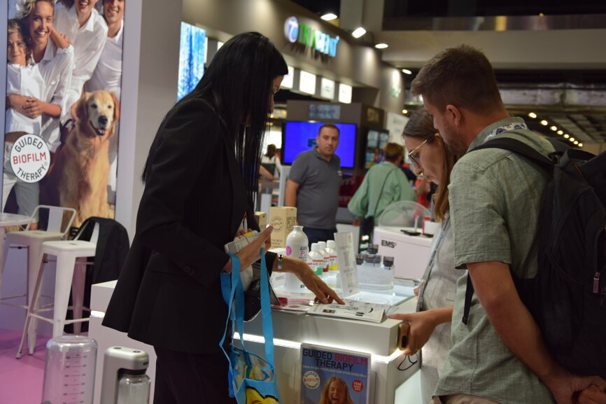 Participants engaging with the latest precision dentistry devices at the EMS booth.