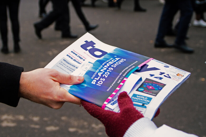 Dental professionals receiving the today at IDS newspaper from Wednesday. (Photograph: Luke Gribble, DTI)