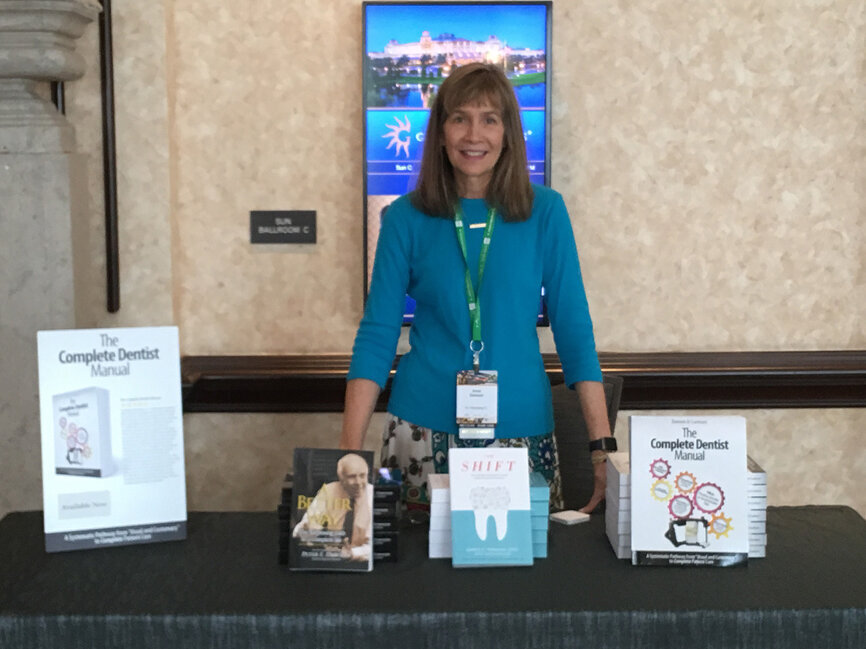 Anne Dawson shows off the collection of books available for sale during The Dawson Academy’s ‘Dawson Seminar 1: Functional Occlusion from TMJ to Smile Design,’ held Thursday at the FDC as part of a special appearance.