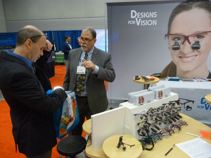 Checking out a new LED DayLite Micro HDi, Ronald Loren Korzinstone, DDS, left, of Lachute, Quebec, receives assistance from Johathan Ratner in the Designs for Vision booth.