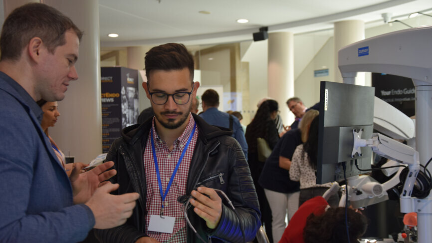 ROOTS SUMMIT attendee getting more information on a surgical loupe from Zumax Medical. 