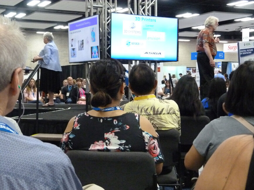With the audience tuned in via earbuds linked to wireless receivers at each seat, Mary Govoni, CDA, RDH, presents ‘Ergonomics for personal and practice longevity’ as Paul Feuerstein, DMD, simultaneously presents ‘Diagnosis, planning and treatment using new 3-D technology’ on the main stage of The Digital Future of Dentistry Technology Expo. (Photo: Robert Selleck/DTA)