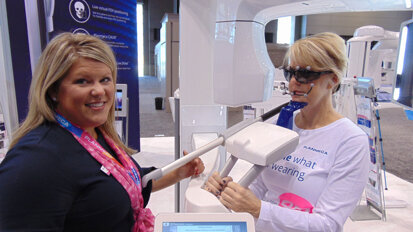 Jennifer Horwath, left, and Kyle Hansen demonstrate the new Planmeca Viso imaging system, making its debut at AAOMS 2018. (Photo by Fred Michmershuizen/Dental Tribune USA)