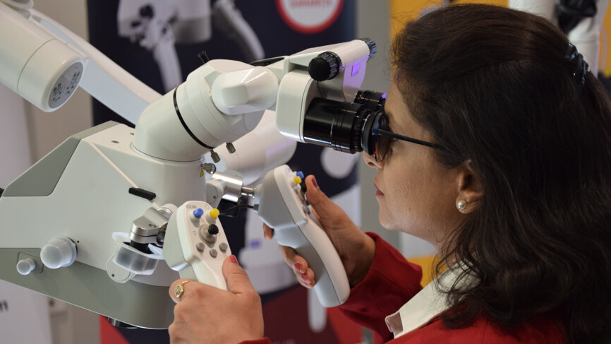 Attendee trying out a surgical magnification device from Zumax Medical. 