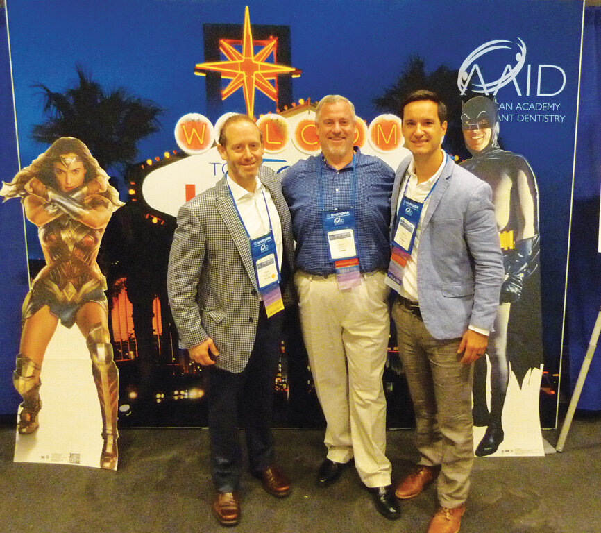 Adam Foleck, Justin Moody and Danny Domingue stop in at the interactive AAID booth promoting next year’s annual meeting, to take place in Las Vegas. Photo by Sierra Rendon/DTA