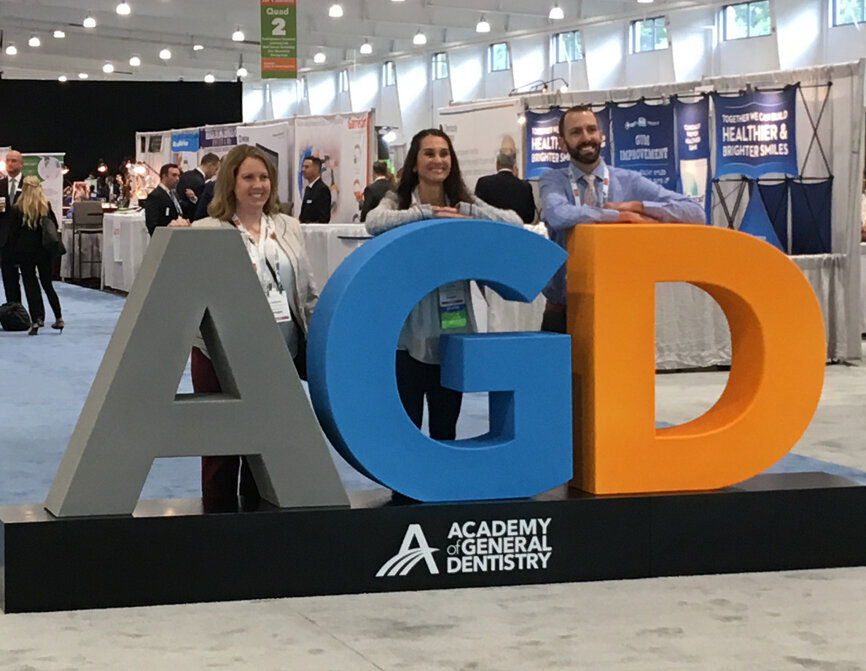 Attendees gather around the AGD sign greeting visitors to the exhibit hall on the first day of the AGD2019 annual scientific session, held at the Mohegan Sun in Uncasville, Conn.