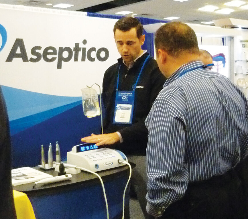 Chris Berry shows an attendee the benefits of the Aseptico implant motor. Photo by Sierra Rendon/DTA