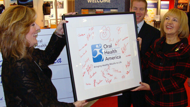 Henry Schein presents check and new logo design to OHA