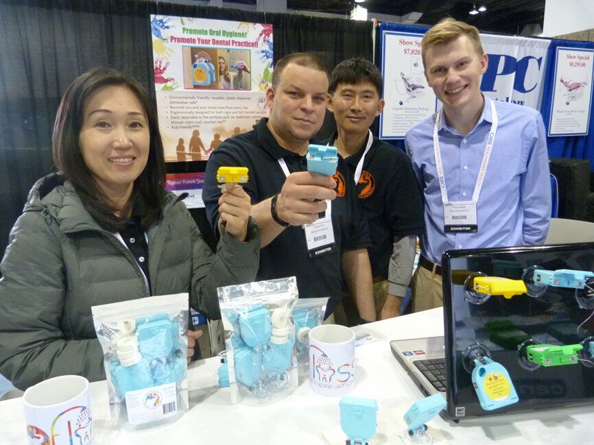 At their first dental meeting, the team at Ofloss International display the just launched Ofloss dental floss dispenser, which suction-cup mounts to you mirror, shower wall or another smooth surface to help remind you to floss daily. The patented device has multiple cutters that enable easy right-handed, left-handed and even one-handed access. From left, Miki Chung, Cecilio Soto, the inventor Brett Chung and Peter Wardell. (Photo: Robert Selleck/Dental Tribune America)