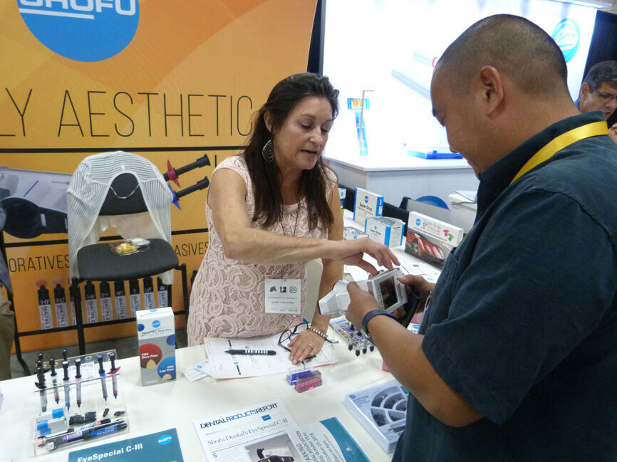 Carrie Maggard, with Shofu Dental Corp., helps Craig Nunokawa, DDS, of Wailuku, Hawaii, check out the EyeSpecial CIII dental camera. (Photo: Robert Selleck/DTA)