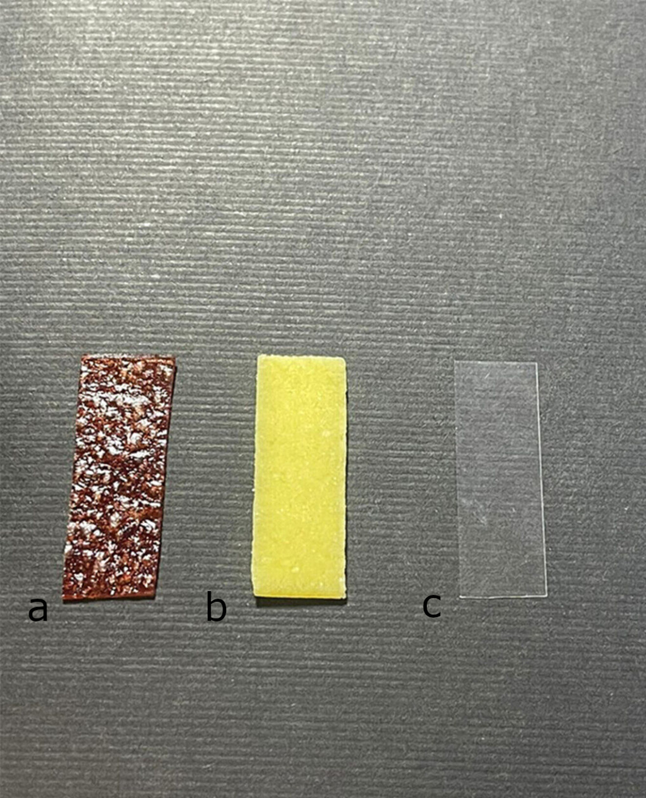 Owocowy pasek w posaci żelka (grubość: 1 mm; a), guma do żucia (grubość: 1 mm; b) i matryca celuloidowa (grubość: 5 μm; c). (Zdjęcie: © 2024 Mokhtari et al., Journal of Medical Radiation Sciences, licencja: CC BY 4.0)